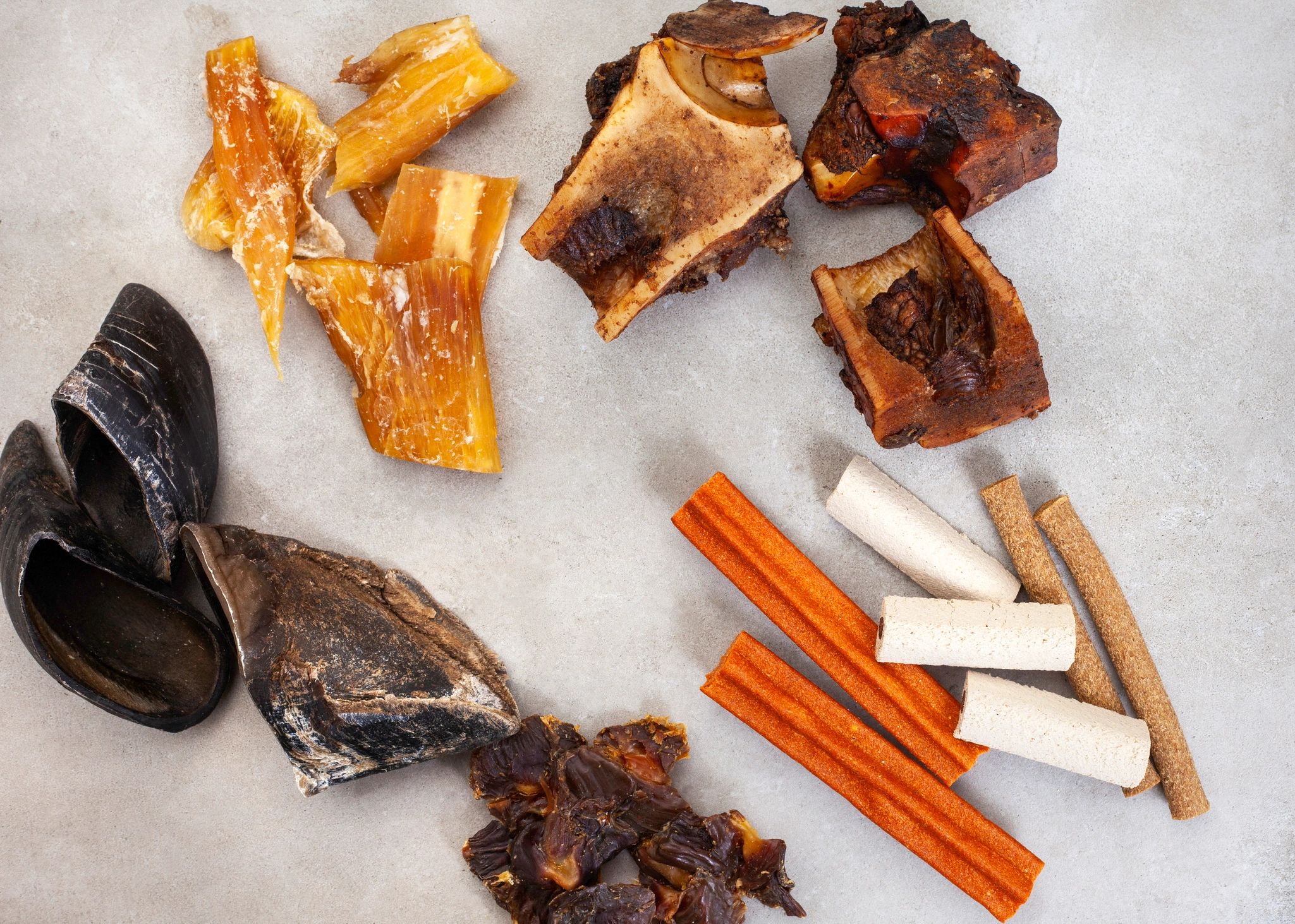 Assorted dog treats and chews on a grey surface